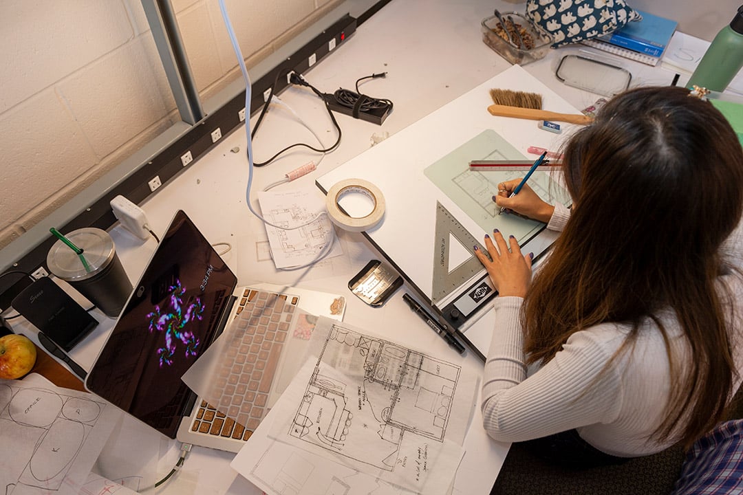 an architecture student working on floor plans at a work station