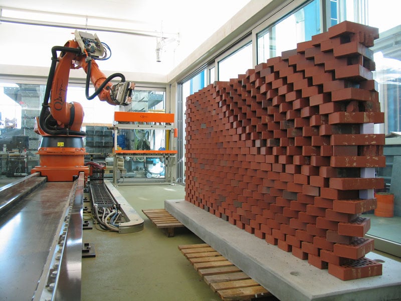 a robotic arm laying bricks in a pattern inside a lab