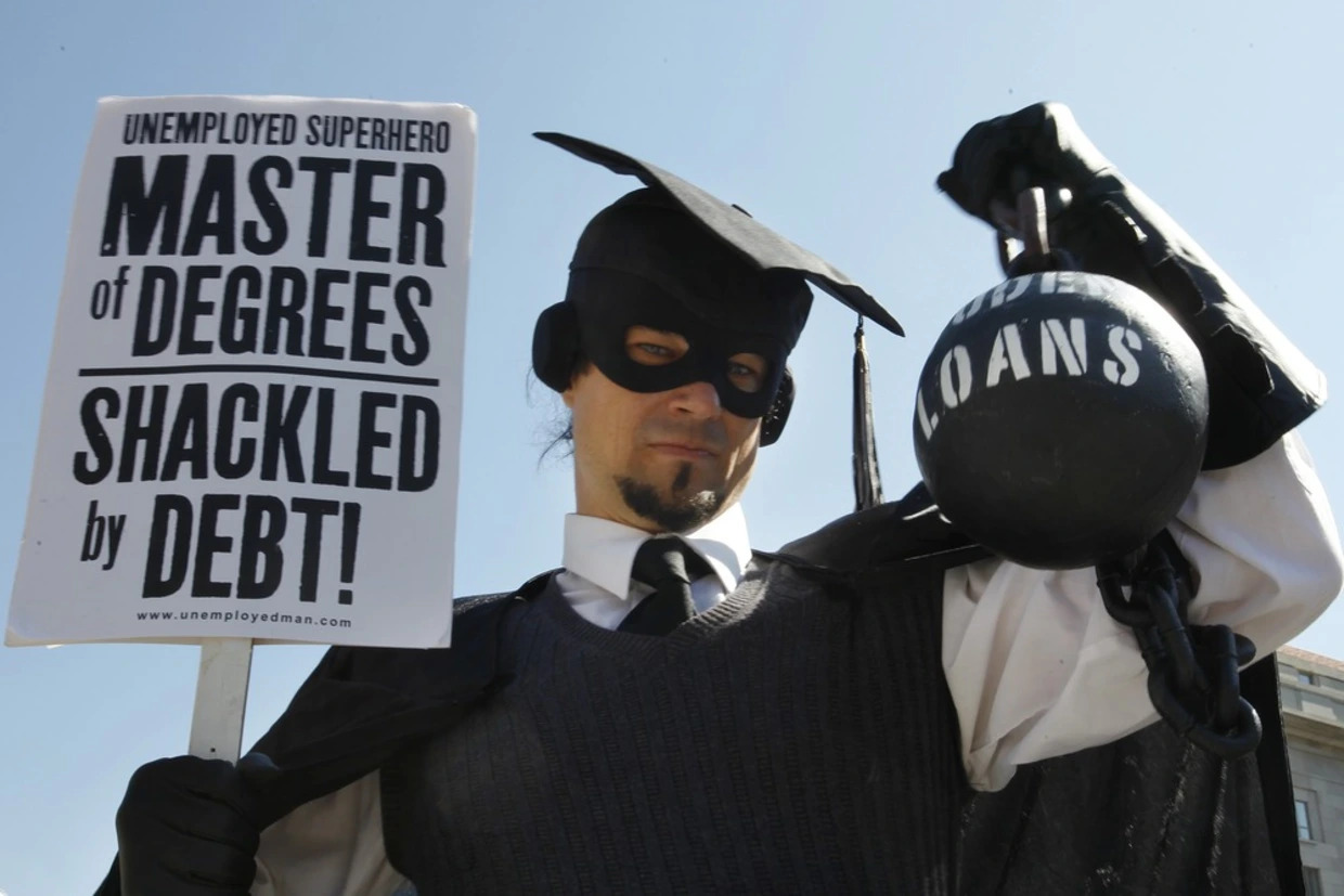 a protestor wearing graduation robes and caps holding a sign