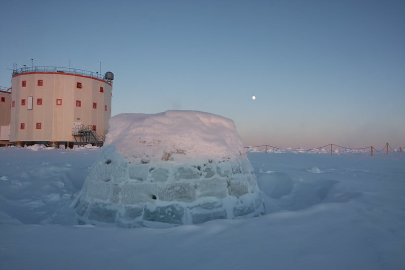 An igloo next to a research station in the icy landscape of Antarctica