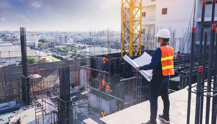 A civil engineer holding a blueprint while overseeing the site progress.