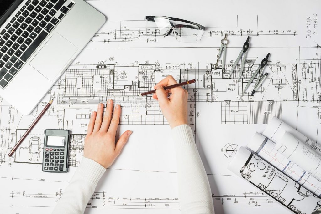 A person working on working drawings on a desk