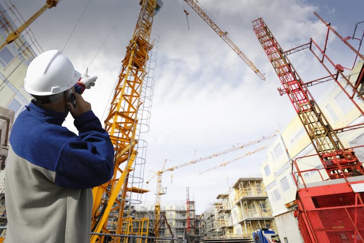 Construction manager supervising machinery on site