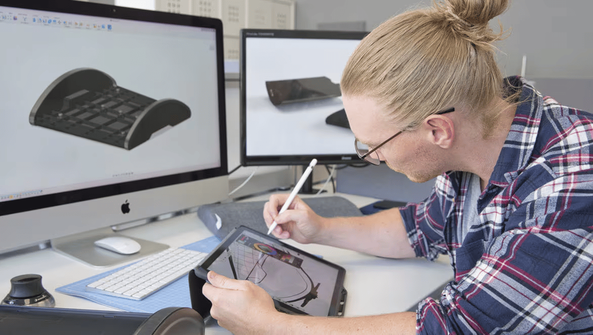 Designer reviewing 3D model on multiple screens.