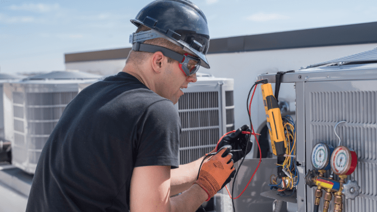 HVAC technician testing electrical connections on rooftop cooling equipment