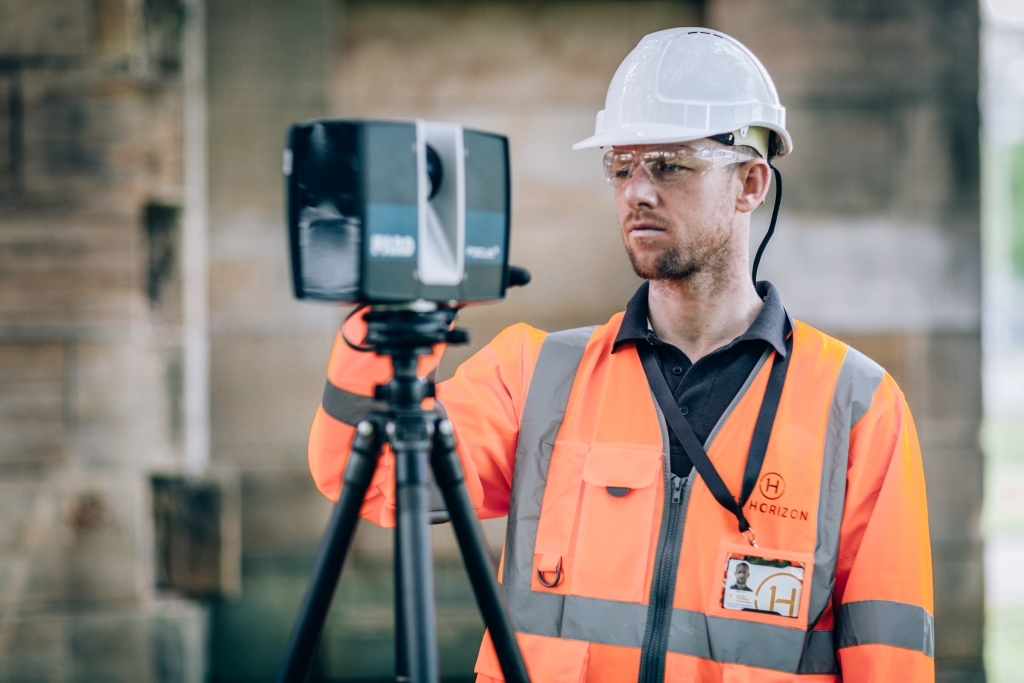 An engineer holding a 3D laser scanner on a tripod