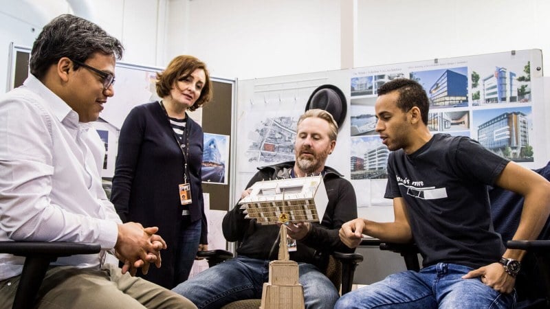 Managers and employees discussing a building model