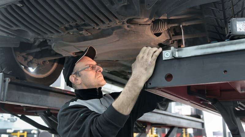 Mechanic inspecting vehicle underside