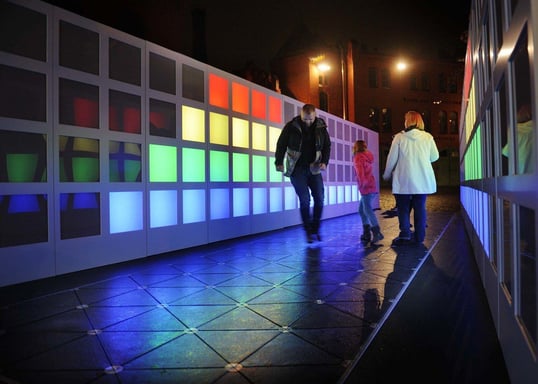 People Walking on kinetic paving which lights up the surrounding lights