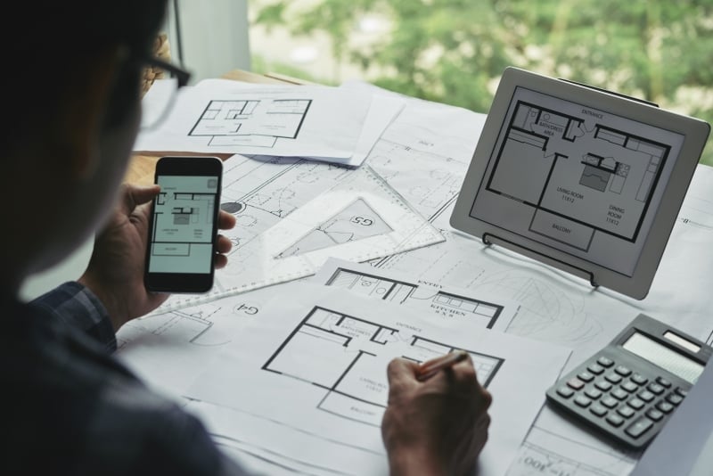 Over-the-shoulder view of a designer working with blueprints.
