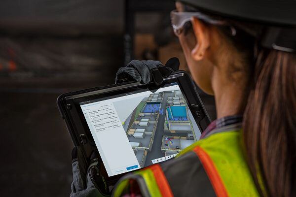 Woman architect in safety gear watching 3D model of a building