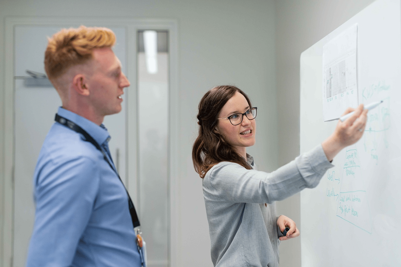 MEP engineers discussing plans on a whiteboard.